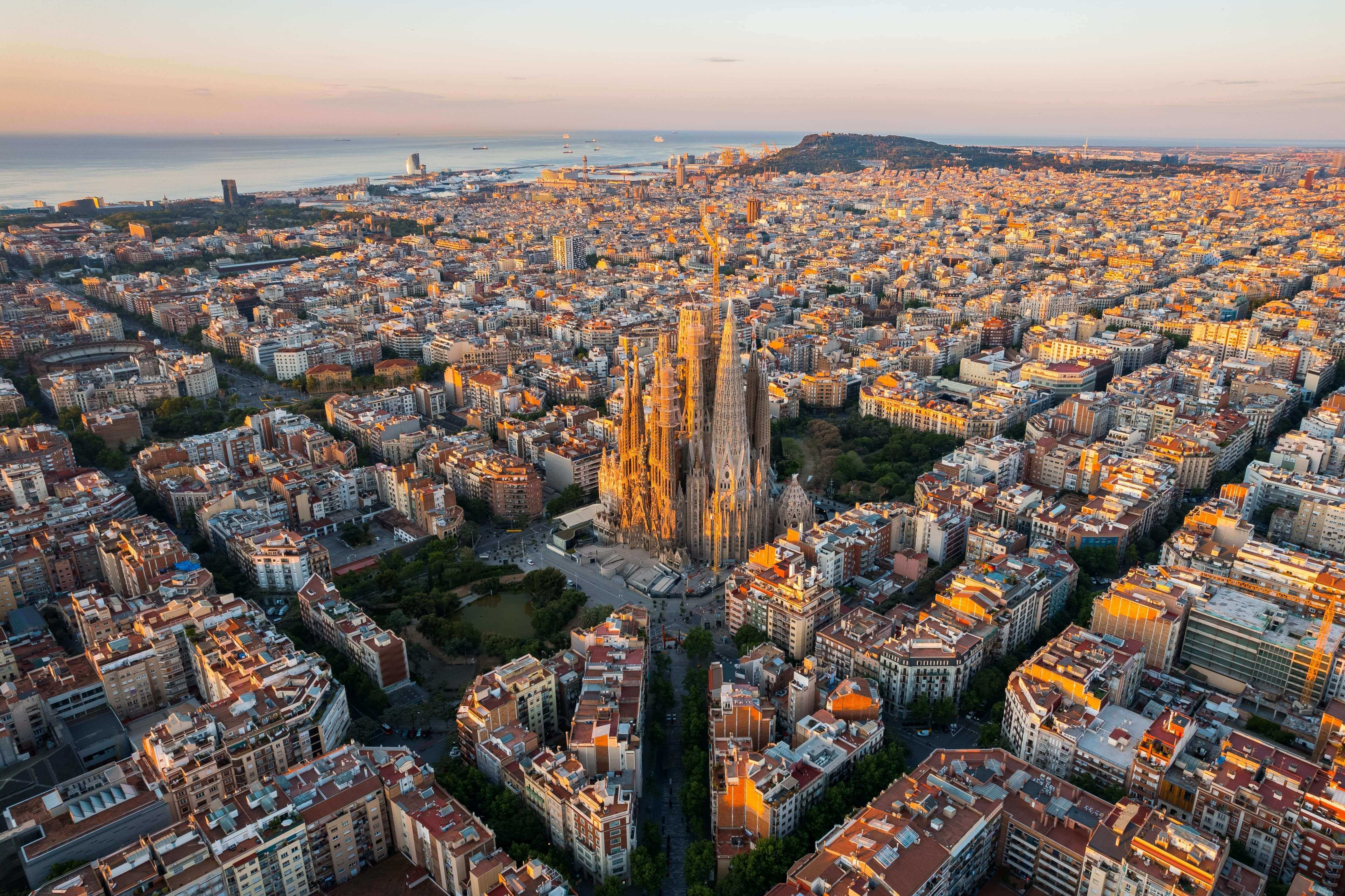 Aerial view of Barcelona Eixample residential district and Sagrada Familia Basilica at sunrise.